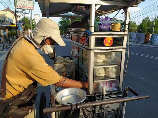 Beny, pedagang bakpao keliling melayani pembeli di kawasan Jalan Wahidin Kota Cirebon, Selasa (20/7/2021). FOTO:  Anatasya/CIREMAITODAY