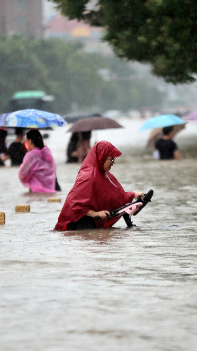 Warga mengarungi banjir di jalan di Zhengzhou, provinsi Henan, Cina, Selasa (20/7). Foto: cnsphoto via REUTERS