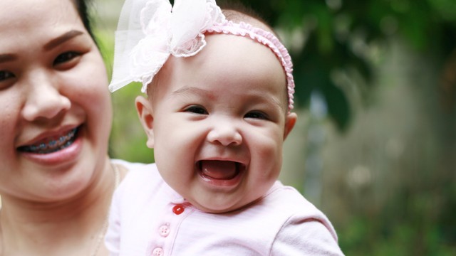 Ilustrasi bayi tertawa saat digendong ibu. Foto: Shutter Stock