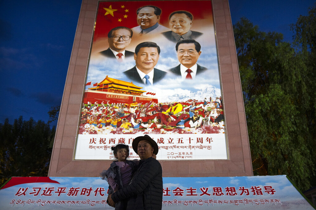 Warga berfoto di depan poster Presiden China Xi Jinping dan para pemimpin China lainnya di Daerah Otonomi Tibet China barat pada 1 Juni 2021. Foto: Mark Schiefelbein/AP