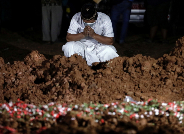 Warga berziarah di dekat pusara keluarganya di area pemakaman khusus COVID-19 di Bekasi, Jawa Barat, Selasa (27/7). Foto: Willy Kurniawan/REUTERS