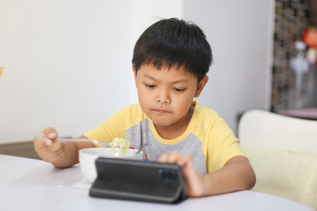 Ilustrasi anak main gadget sambil makan. Foto: Shutter Stock
