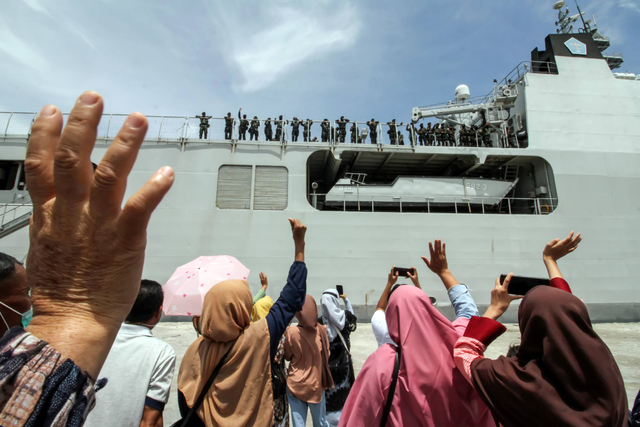 Keluarga melambaikan tangan kepada prajurit Raider TNI yang diberangkatkan dengan kapal TNI Angkatan Laut di Pelabuhan Umum Krung Geukuh, Aceh Utara, Aceh, Kamis (29/7/2021). Foto: Rahmad/Antara Foto