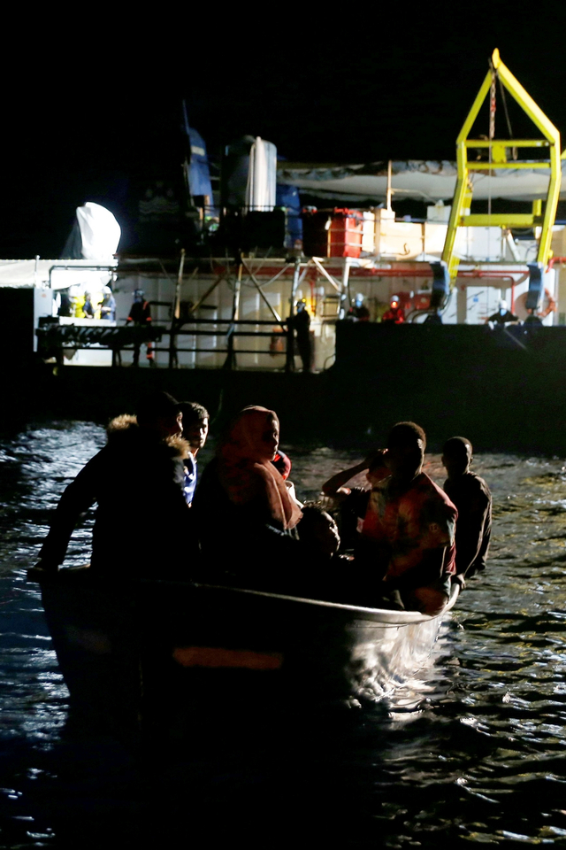 Para migran ke perahu kayu mereka dari kapal Penjaga Pantai Libya setelah kapal penyelamat migran LSM Jerman Sea-Watch 3 mengambil alih operasi penyelamatan di lepas pantai Libya, di Laut Mediterania barat, Juli (29/7). Foto: Darrin Zammit Lupi/REUTERS