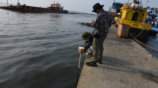 Petugas rekanan Kementerian PUPR melakukan pengukuran koordinat menggunakan alat GPS Geodetik terkait rencana pembangunan tanggul laut di Pelabuhan Kali Adem, Jakarta, Jumat (30/7/2021). Foto: Indrianto Eko Suwarso/ANTARA FOTO