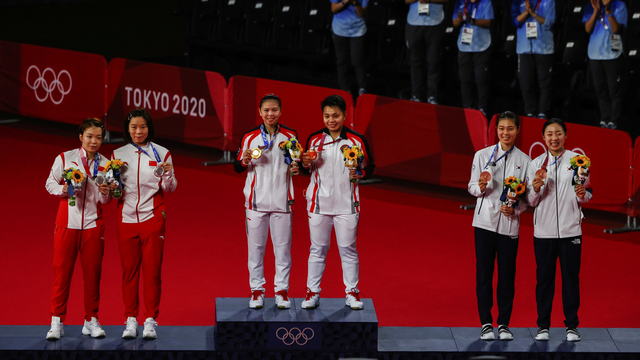 Atlet Indonesia Apriyani Rahayu dan Greysia Polii (tengah) berdiri di podium saat mendapatkan medali emas bulu tangkis ganda putri pada upacara Olimpiade Tokyo 2020, Senin (2/8).
 Foto: Hamad I Muhammad/REUTERS