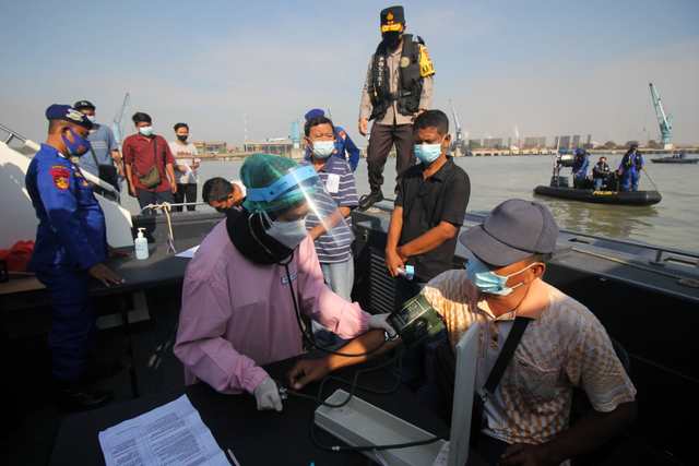 Petugas kesehatan memeriksa tekanan darah warga sebelum disuntik vaksin COVID-19 saat Vaksinasi Merdeka di atas kapal patroli Polairud Polda Jawa Timur di perairan Lumpur, Gresik, Jawa Timur, Selasa (3/8). Foto: Didik Suhartono/ANTARA FOTO
