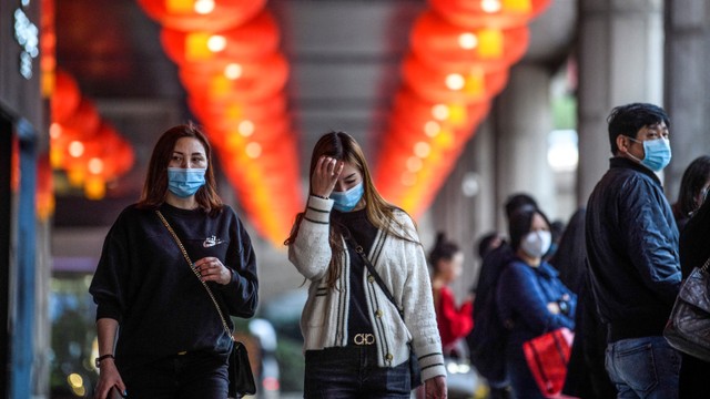 Pejalan kaki mengenakan masker saat berjalan di jalanan Makau. Foto: ANTHONY WALLACE / AFP