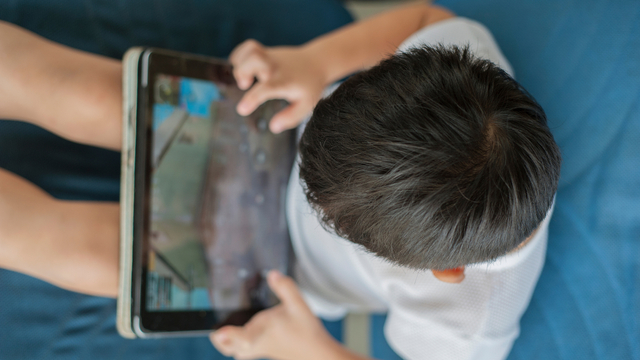 Ilustrasi anak memakai gadget untuk bermain game online. Foto: Shutter Stock