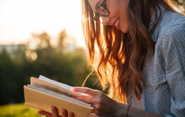 Sumber. Cropped gambar tersenyum wanita berambut cokelat di kacamata membaca buku di taman/shutterstock.