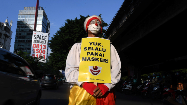 Anggota komunitas Aku Badut Indonesia (ABI) melakukan aksi kampanye prokes dengan membawa poster di kawasan Fatmawati Jakarta, Senin (12/7/2021). Foto: Wahyu Putro A/ANTARA FOTO