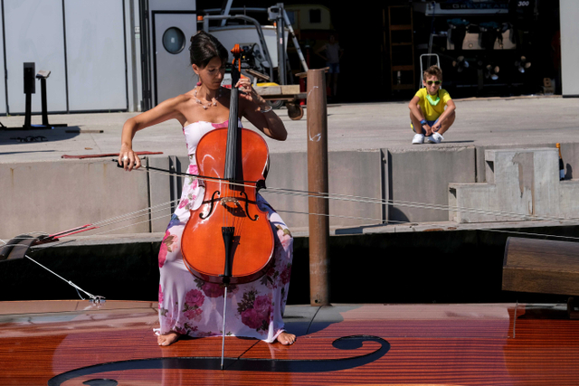 Seorang musisi memainkan cello di atas perahu berbentuk biola, yang dibuat oleh seniman Livio De Marchi. Foto: Manuel Silvestri/Reuters
