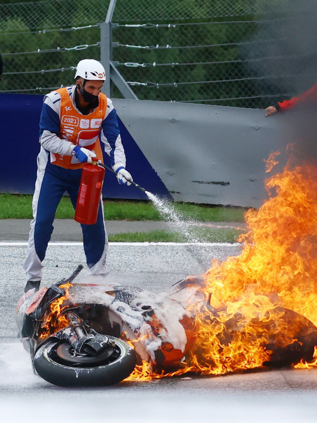 Petugas berusaha memadamkan motor yang terbakar akibat kecelakaan pada ajang MotoGP Styria, Minggu (8/8). Foto: BORUT ZIVULOVIC/REUTERS