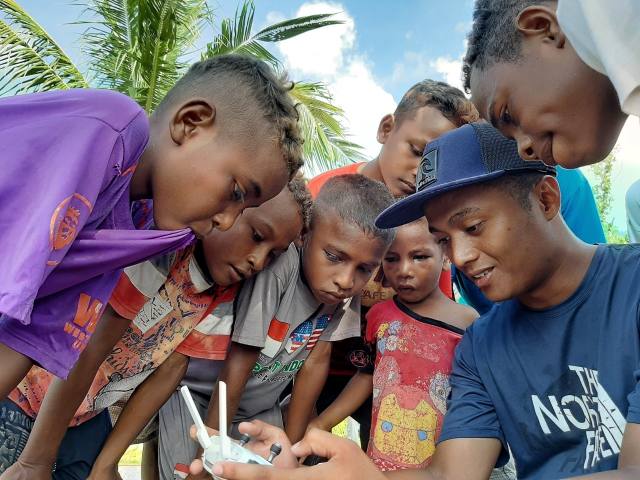 Peneliti WRI Indonesia menjelaskan cara kerja drone kepada anak-anak di Papua Barat. Kredit foto: Rizky Haryanto/WRI