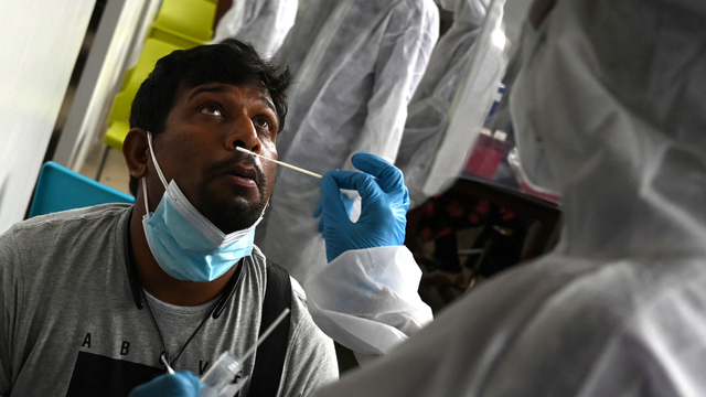 Seorang petugas kesehatan mengumpulkan sampel swab PCR di Chennai, India. Foto: Arun SANKAR/AFP