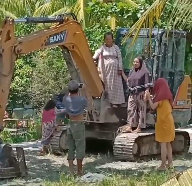 Emak-emak di Sambas berfoto di excavator. Foto: Instagram @sambasinformasi