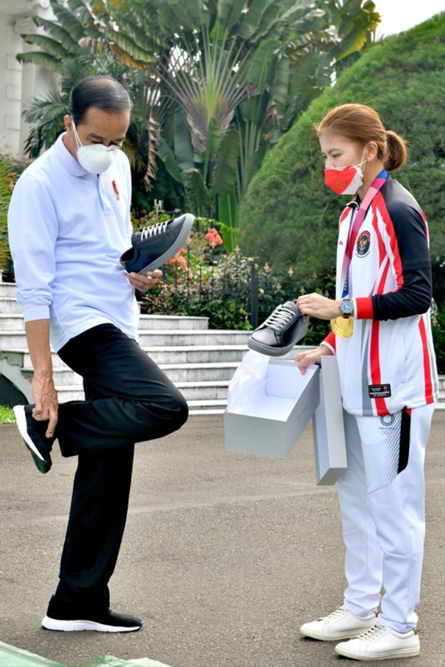 Atlet bulu tangkis Indonesia Greysia Polii saat menawarkan sepatu ke Presiden Jokowi. Foto: Agus Suparto/Istana Presiden