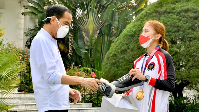 Atlet bulu tangkis Indonesia Greysia Polii saat menawarkan sepatu ke Presiden Jokowi. Foto: Agus Suparto/Istana Presiden