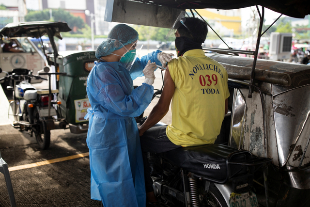 Petugas kesehatan memberikan vaksin corona kepada pengemudi angkutan umum di tempat vaksinasi drive-thru, Quezon City, Metro Manila, Filipina. Foto: Eloisa Lopez/REUTERS