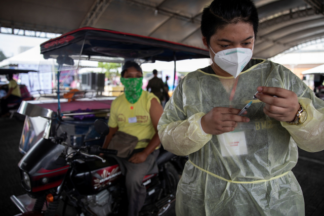 Petugas kesehatan memberikan vaksin corona kepada pengemudi angkutan umum di tempat vaksinasi drive-thru, Quezon City, Metro Manila, Filipina. Foto: Eloisa Lopez/REUTERS