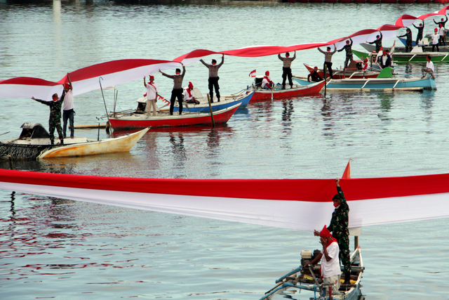 Sejumlah anggota TNI, Polri dan nelayan membentangkan bendera merah putih di perairan Pantai Losari, Makassar, Sulawesi Selatan, Selasa (17/8/2021). Foto: Arnas Padda/Antara Foto