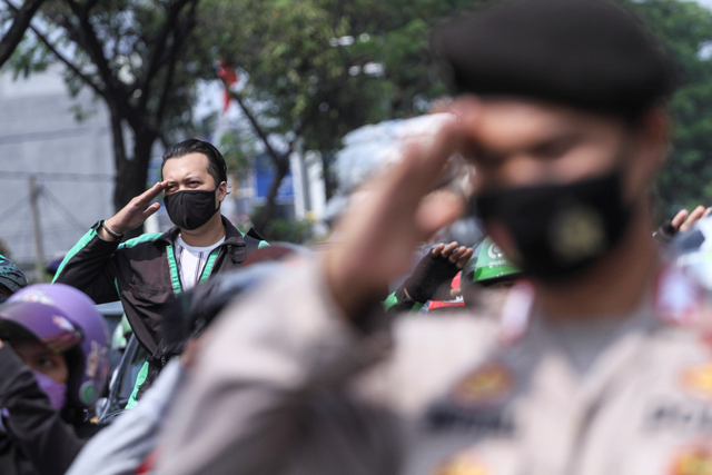 Pengendara dan petugas kepolisian memberi hormat saat melakukan sikap sempurna di Jalan Margonda Raya, Depok, Jawa Barat, Selasa (17/8/2021). Foto: Asprilla Dwi Adha/Antara Foto