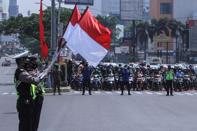 Petugas kepolisian mengibarkan bendera merah putih saat melakukan sikap sempurna di Jalan Margonda Raya, Depok, Jawa Barat, Selasa (17/8/2021). Foto: Asprilla Dwi Adha/Antara Foto
