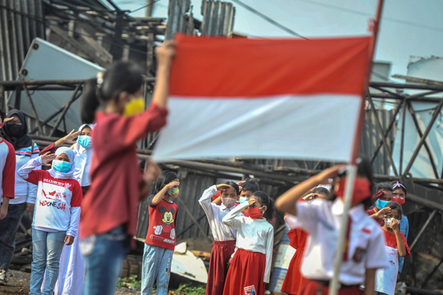 Anak-anak dari Komunitas Kelas Jurnalis Cilik mengikuti upacara bendera di kawasan Belah Kapal, Cilincing, Jakarta, Selasa (17/8/2021). Foto: Aprillio Akbar/Antara Foto