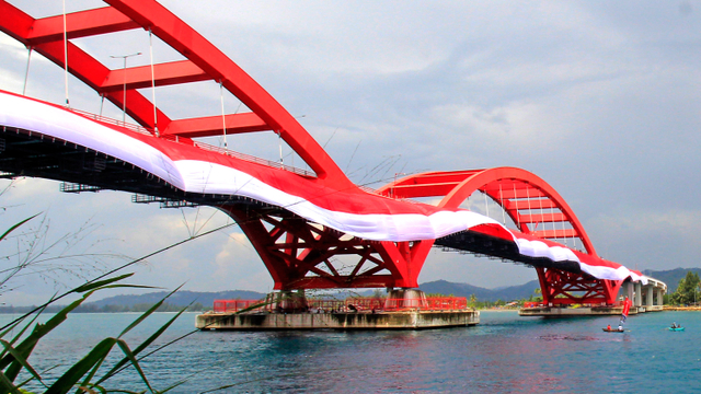 Nelayan melintasi Jembatan Youtefa yang dipasang  bendera Merah Putih di Jayapura, Papua, Selasa (17/8/2021). Foto: Gusti Tanati/ANTARA FOTO