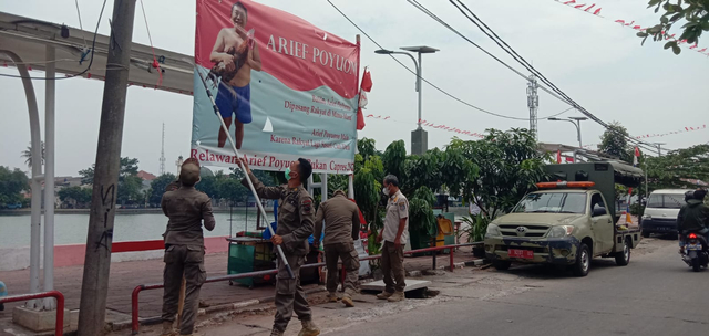 Petugas Satpol PP Kota Depok menurunkan baliho diduga mirip Arif Poyuono. Foto: Dok. Istimewa
