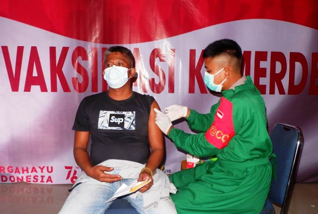 Salah seorang warga tengah disuntikkan vaksin oleh seorang tim Medis dari Anggota Brimob Polda Sultra. Foto: Deden Saputra/kendarinesia.