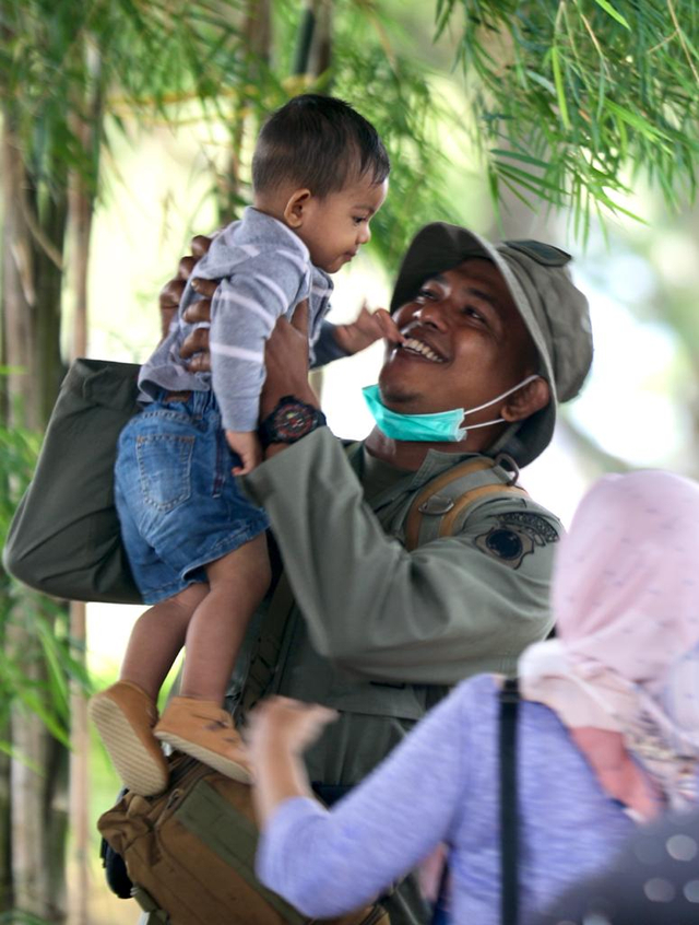 Seorang personel Brimob Polda Aceh menggendong anaknya sesaat akan diberangkatkan ke Papua dari Bandara Sultan Iskandar Muda, Minggu (22/8/2021). Foto: Suparta/acehkini