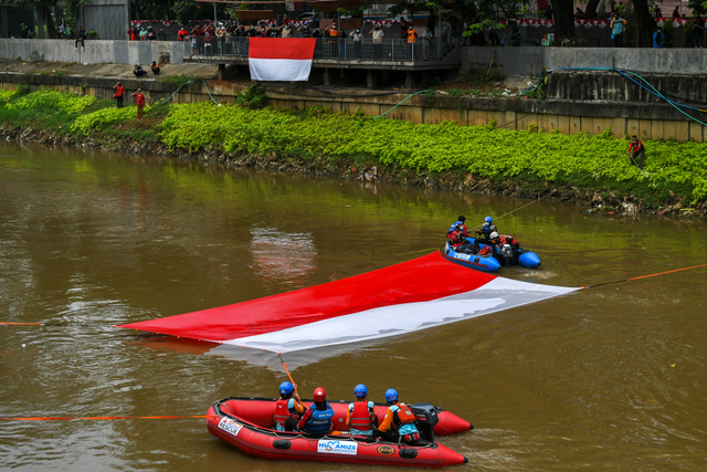 Gabungan relawan rescue membentangkan bendera Merah Putih ukuran 10x5 meter di Kali Ciliwung, Jakarta, Minggu (22/8/2021). Foto: Galih Pradipta/ANTARA FOTO