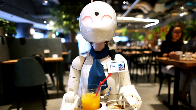 Robot humanoid mengantarkan minuman kepada pelanggan di Dawn Cafe di Tokyo. Foto: BEHROUZ MEHRI/AFP