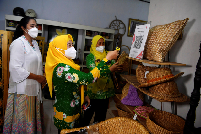 Perajin rajut yang juga pemilik UMKM WIn's Rajut Winarsih (kiri) mengamati pelanggannya melakukan transaksi secara QRIS di UMKM Win's Rajut, Pasuruan, Jawa Timur. Foto: Zabur Karuru/ANTARA FOTO