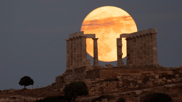 Bulan purnama sturgeon muncul di belakang kuil marmer kuno Poseidon di Cape Sounion, Athena, Yunani, Sabtu (21/8). Foto: Michael Varaklas/AP Photo