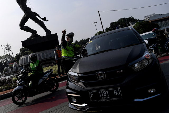 Polisi mengatur lalu lintas kendaraan di pos penerapan ganjil genap di kawasan Bundaran Senayan, Jakarta, Selasa (24/8/2021). Foto: Sigid Kurniawan/Antara Foto