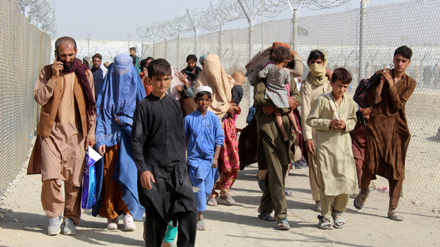 Warga Afghanistan berjalan di sepanjang pagar ketika mereka tiba di Pakistan melalui titik penyeberangan perbatasan Pakistan-Afghanistan di Chaman, Selasa (24/8). Foto: AFP
