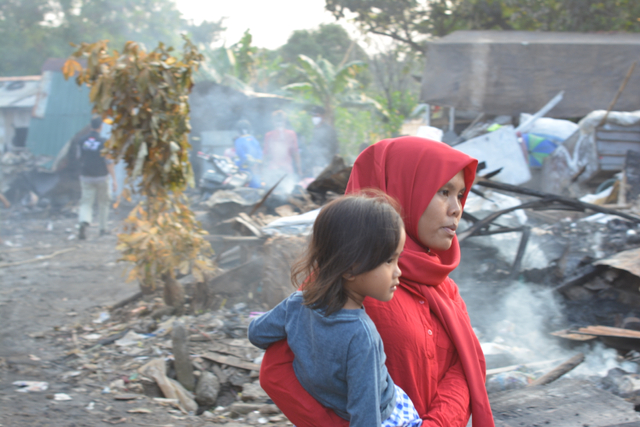 Warga kampung pemulung bersama anaknya berjalan di antara bekas rumah yang habis terbakar di kampung pemulung, Jurangmangu Barat, Pondok Aren, Tangerang Selatan, Rabu (25/8). Foto: Ayyub/MRI-ACT