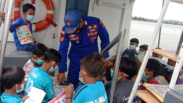 Anggota Satpolairud Polresta Barelang tengah mengajar anak-anak membaca di atas kapal. Foto: Dok Polairud Polresta Barelang.