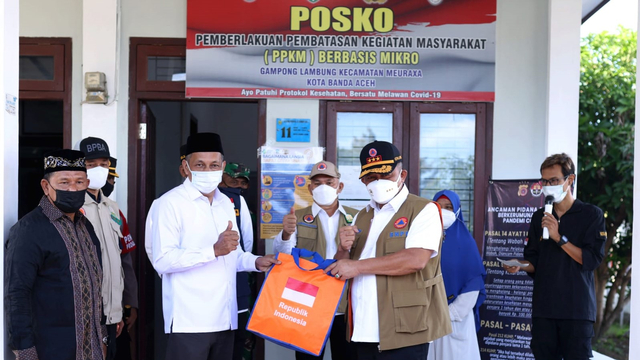 Kepala BNPB, Ganip Warsito menyerahkan bantuan masker kepada Kepala Desa Lambung, Banda Aceh. Foto: Abdul Hadi/acehkini