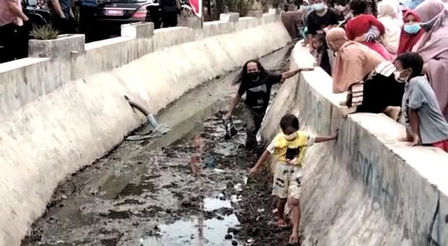 Warga rela nyebur ke saluran air demi menndapat bingkisan dari Presiden Joko Widodo.(Juan)