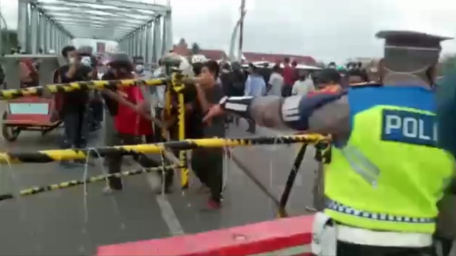 Pengendara memindahkan blokade penyekatan jalan saat PPKM di Lhokseumawe. Foto: Screenshot video