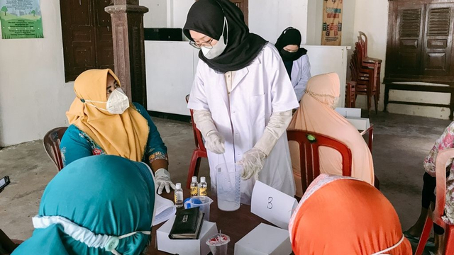 Mahasiswa KKN UNS Kelompok 145 mengajari warga membuat hand sanitizer.