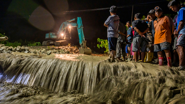 Sejumlah warga menyaksikan alat berat membersihkan material lumpur yang memenuhi aliran sungai dan jalan di Desa Beka, Sigi, Sulawesi Tengah, Jumat (3/9/2021). Foto: Basri Marzuki/ANTARA FOTO