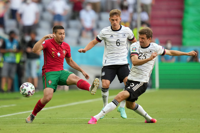 Pemain Portugal Raphael Guerreiro berebut bola dengan pemain Jerman Thomas Mueller pada pertandingan lanjutan Grup F Euro 2020 di Allianz Arena, Muenchen, Jerman. Foto: Matthias Schrader/Pool/REUTERS