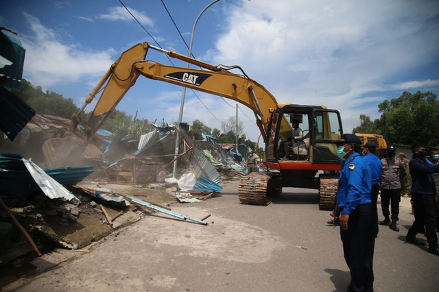 Alat berat melakukan pembongkaran bangunan ruma liar disepanjang jalan industri Tanjung Uncang, Batam. Foto: Rega/kepripedia.com