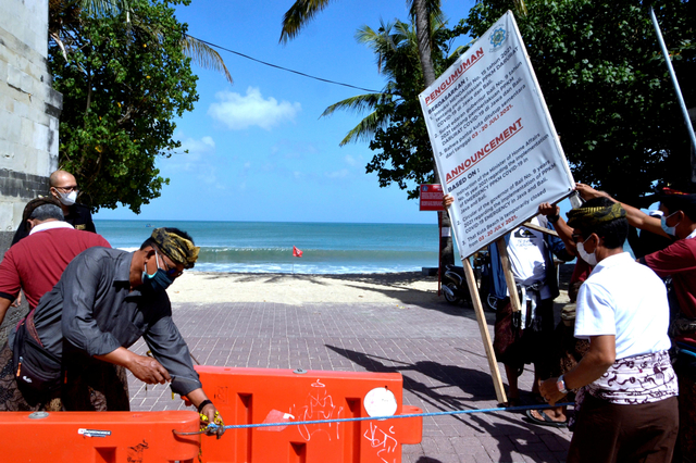 Petugas membuka akses masuk kawasan wisata Pantai Kuta di Badung, Bali, Rabu (8/9/2021).  Foto: Fikri Yusuf/Antara Foto