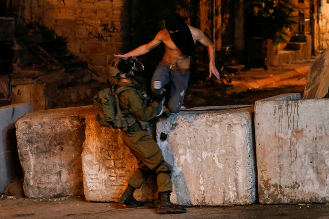 Seorang anggota pasukan Israel bentrok dengan seorang demonstran selama protes solidaritas dengan tahanan, di Hebron di Tepi Barat yang diduduki Israel, Kamis (9/9). Foto: Mussa Qawasma/REUTERS