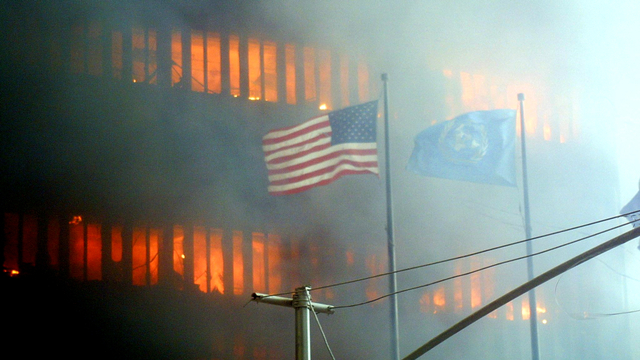 Bendera Amerika berkibar di latar depan saat salah satu menara World Trade Center terbakar di New York, AS, pada 11 September 2001. Foto: Doug KANTER/AFP